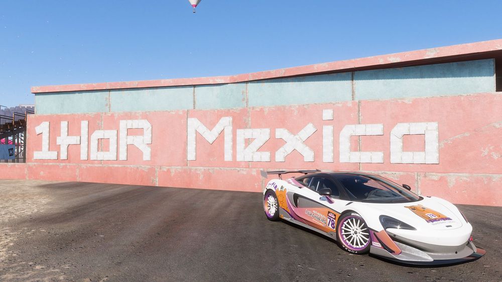 A sports car is posed in front of a 1HOR Mexico wall.