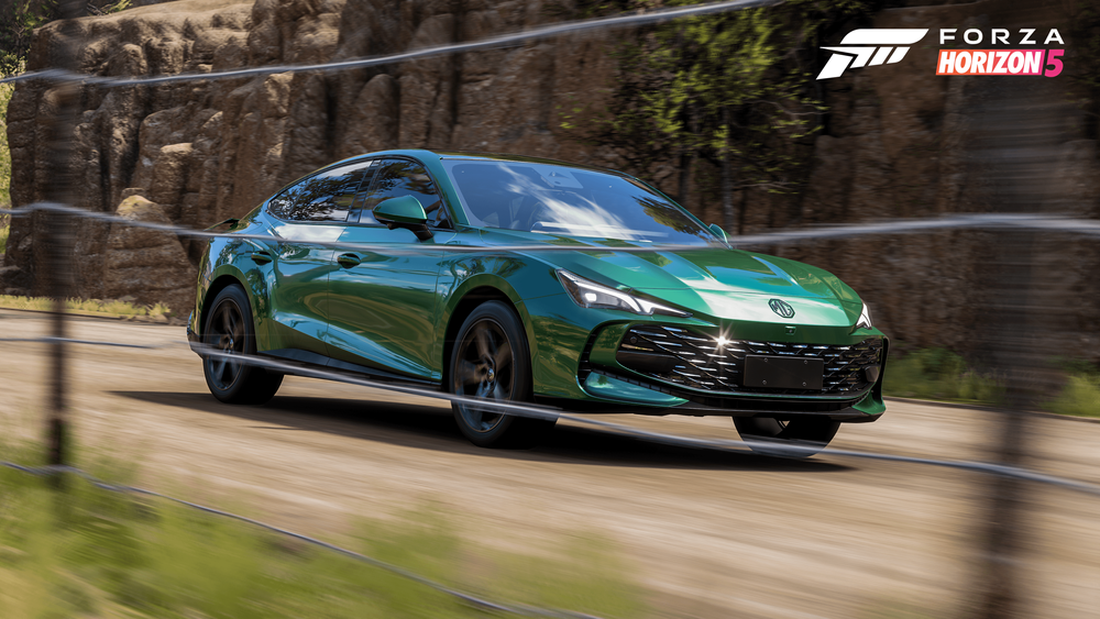 Green sports car rushig through a dirt road in front of a mountain