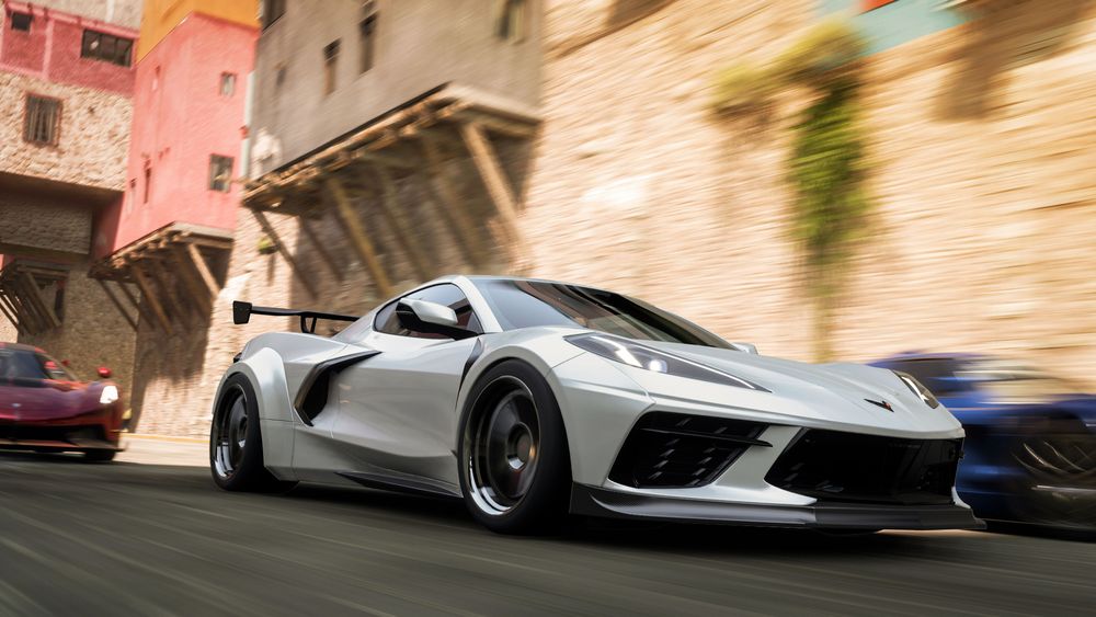 A widebody Corvette races through a town.