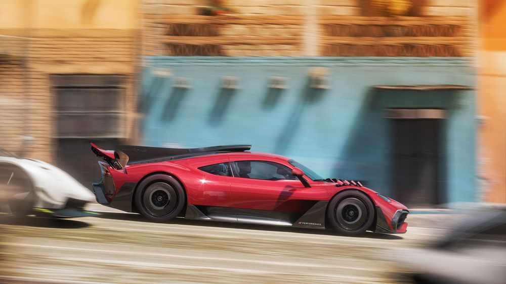 The Mercedes-AMG ONE races past a town shop.