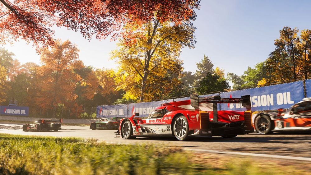 Formula 1 race cars zooming around a track with fall trees in the background.