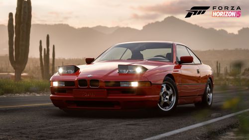 BMW with its headlights turned on parked on a highway in the desert