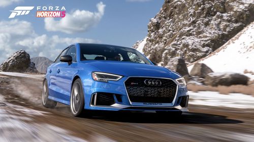 Audi car speeding down a snowy mountain road.