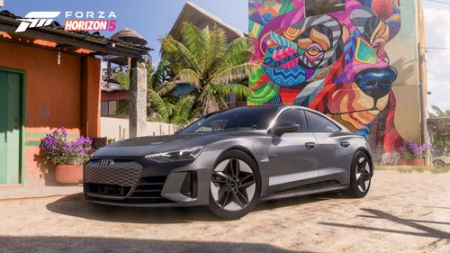 A grey Audi RS e-tron GT is parked in front of a colorful bear mural in Horizon Mexico.