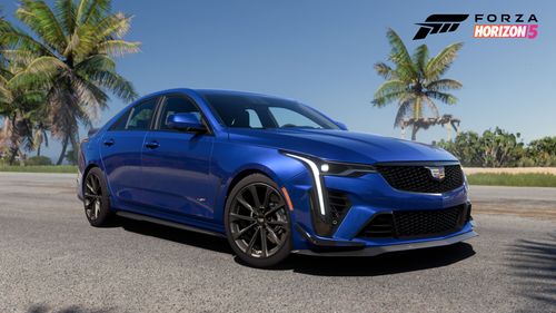An up close photo of the Side view of the blue 2022 Cadillac CT4-V Blackwing parked by palm trees with its front wheels turned right,