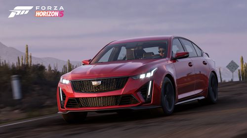 A front view of the red 2022 Cadillac CT5-V Blackwing as it drives on an asphalt road through the arid farmland.