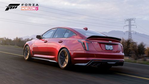 A side view of the red 2022 Cadillac CT5-V Blackwing as it drives on an asphalt road through the arid farmland.
