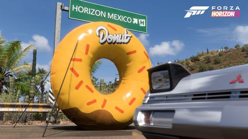 Pop-up headlights of the 1988 Mitsubishi Starion R parked by a Donut shaped Donut Media collectible on the Horizon Highway.