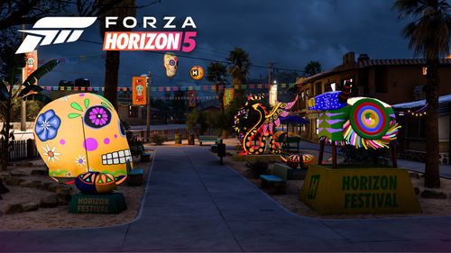 A decorated, inflatable skull in front of some alebrijes decorating a street during the night