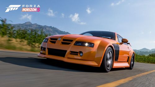 An orange MG XPower driving on the road with green foliage visible in the background.