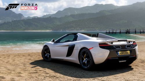 McLaren 650S Spider parked on the beach near the water.