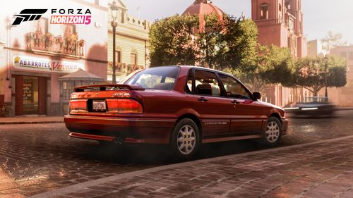 A red Mitsubishi Galant is parked on a town street.