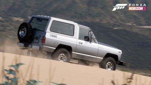 A silver Nissan Safari Turbo drives through the sand.