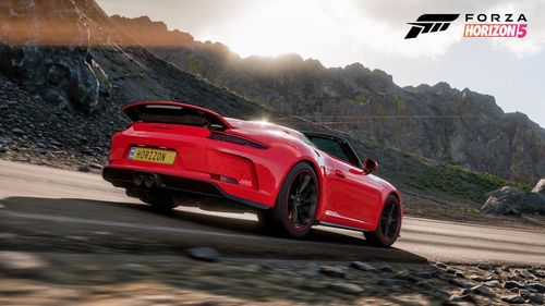 The Porsche 911 Speedster drivers by a rocky landscape.