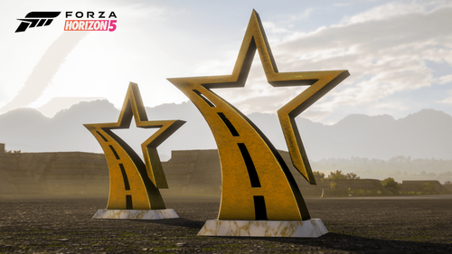 Two star trophies standing on the ground in front of a mountain scenery