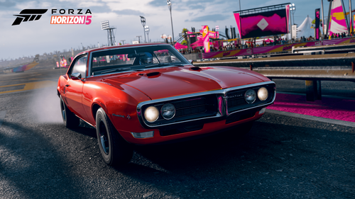 Red Firebird racing through road in front of a pink stage