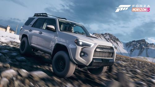 A silver Toyota 4Runner truck takes on a snow-covered rocky landscape.