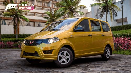 A yellow Wuling Hongguang S parked by buildings and palm trees.