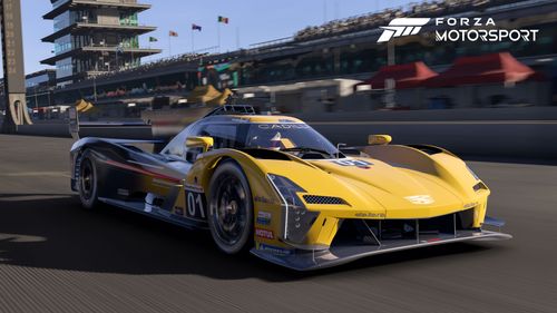 2023 #01 Cadillac Racing V-Series.R in yellow driving at speed down the main straight at Indianapolis. You can see the timing tower, some of the pit area, fans in the flag-lined grandstands, and the famous pagoda.  