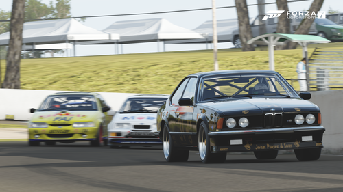 Three sports cars in a race come around a corner on Bathurst.