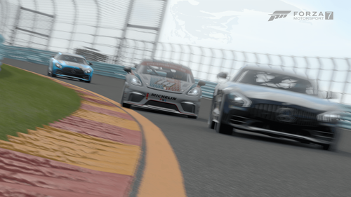 Three cars rounding a bend on a race track.